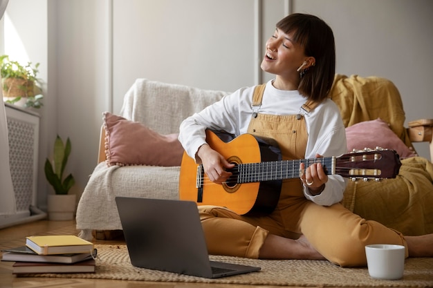 Foto grátis jovem bonita tocando violão dentro de casa