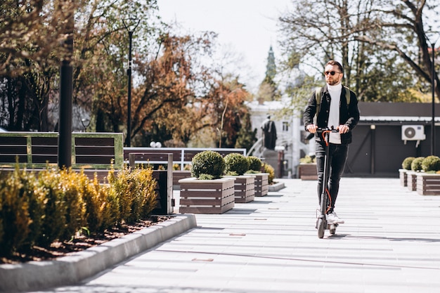 Jovem bonito, andar de scooter no parque