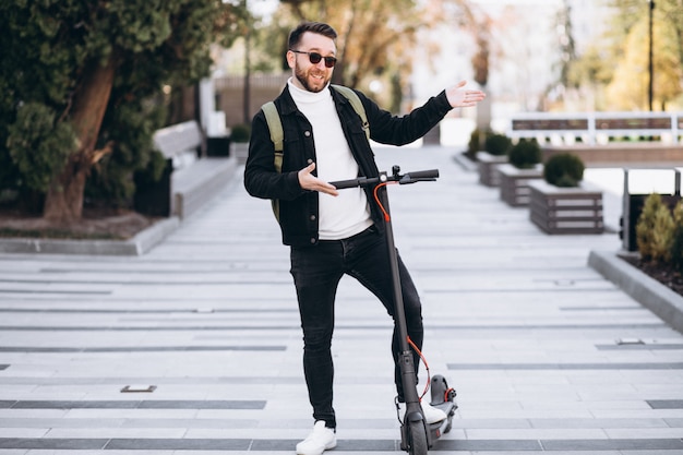 Jovem bonito, andar de scooter no parque