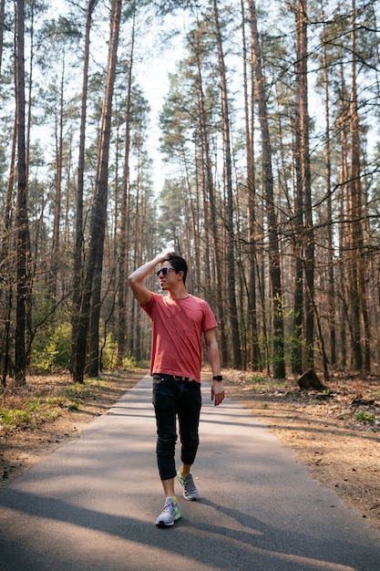 Jovem bonito ao ar livre no parque, caminhando no parque