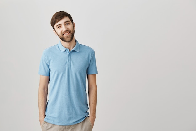 Jovem bonito barbudo sorrindo enquanto posa