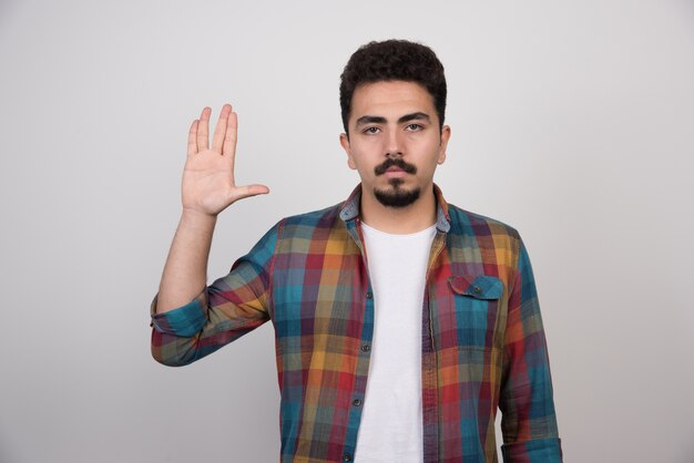 Jovem bonito com barba fazendo gesto de parada.