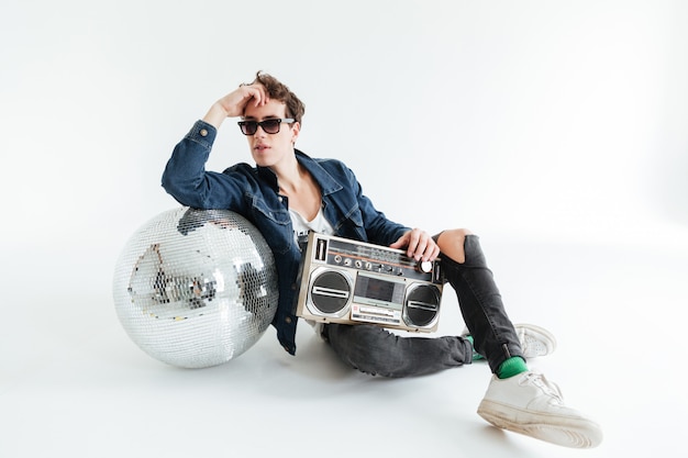 Jovem bonito com bola de discoteca e boombox