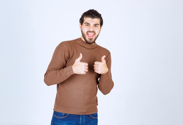 Jovem bonito com polegares para cima e sorrindo.