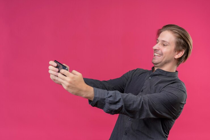 Foto grátis jovem bonito de camisa preta segurando um celular tomando selfie