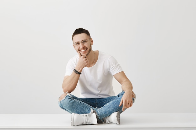 Jovem bonito e alegre com óculos posando