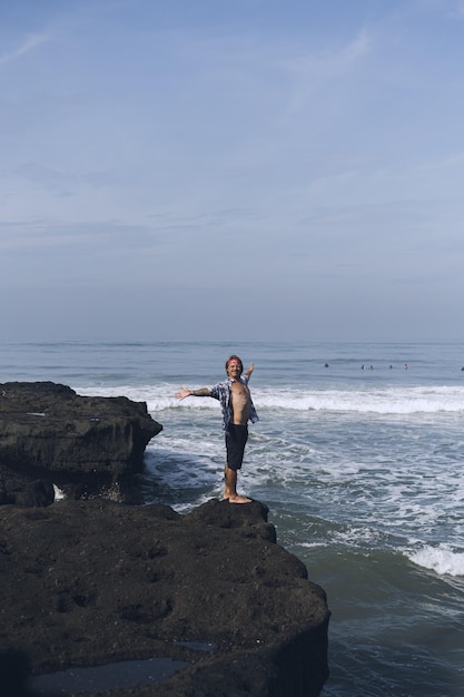 Jovem bonito em uma rocha à beira-mar.