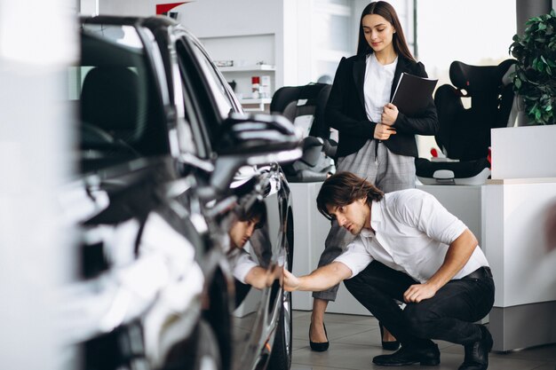 Jovem bonito, escolhendo um carro em uma sala de exposições