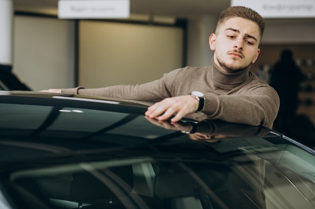 Foto grátis jovem bonito, escolhendo um carro em uma sala de exposições