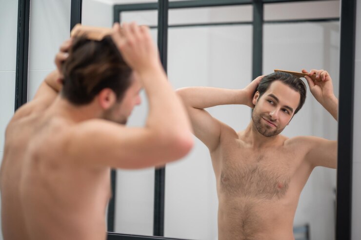 Foto grátis jovem bonito escovando o cabelo e parecendo satisfeito