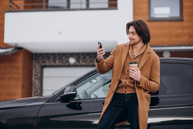 Jovem bonito falando ao telefone de carro