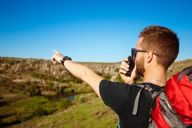 Jovem bonito falando no rádio walkie-talkie, apreciando a vista do canyon