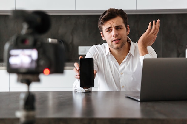 Jovem bonito filmando seu episódio de blog de vídeo