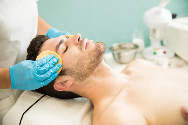 Foto grátis jovem bonito lavando a mão durante uma limpeza facial em um spa de saúde e beleza