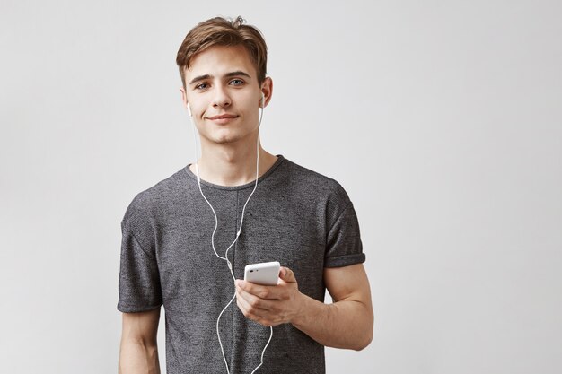 Foto grátis jovem bonito ouve música com fones de ouvido