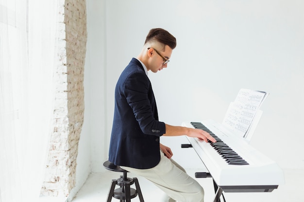 Foto grátis jovem bonito praticando teclado de piano