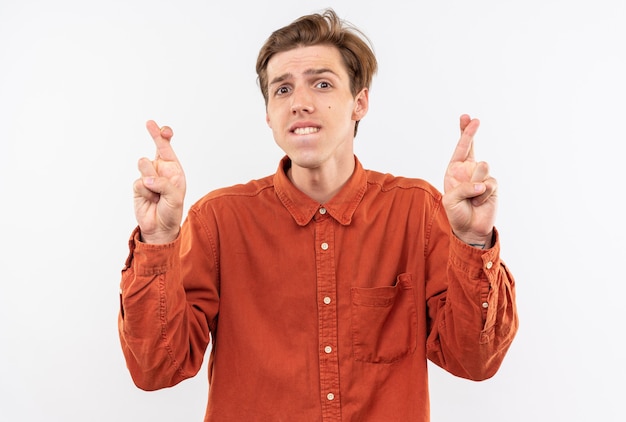 Foto grátis jovem bonito preocupado com uma camisa vermelha cruzando os dedos