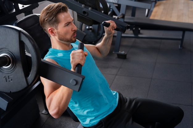 Jovem bonito se exercitando na academia de musculação