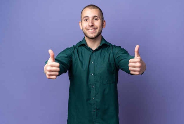 Jovem bonito sorridente com uma camisa verde aparecendo com o polegar para cima