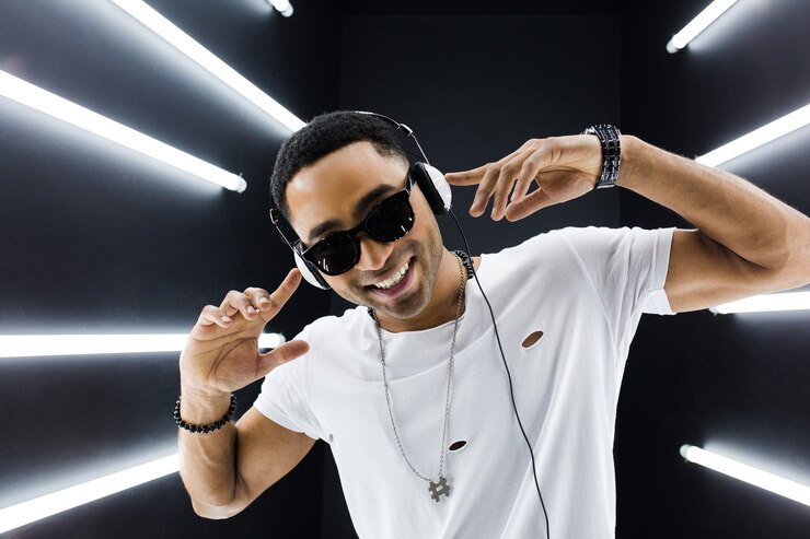 Foto grátis jovem bonito sorridente hipster negro em roupa branca, ouvindo música em fones de ouvido e dançando no estilo hip hop em uma boate discoteca, se divertindo