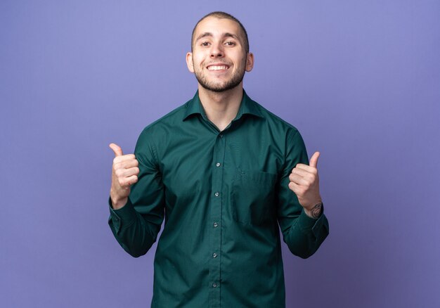 Jovem bonito sorridente usando uma camisa verde mostrando os polegares para cima