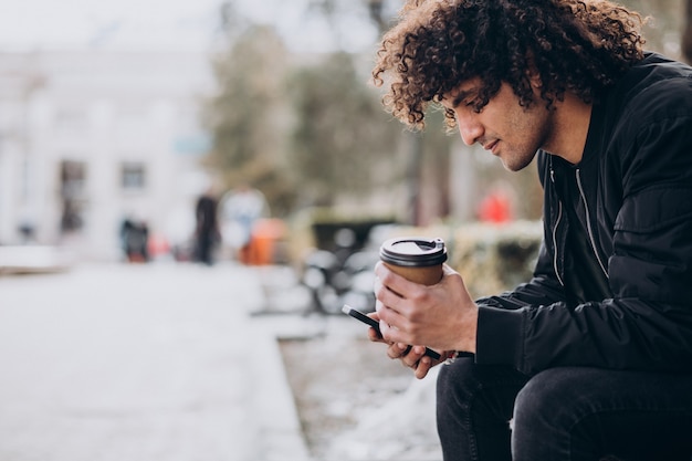 Jovem bonito tomando café e andando na rua