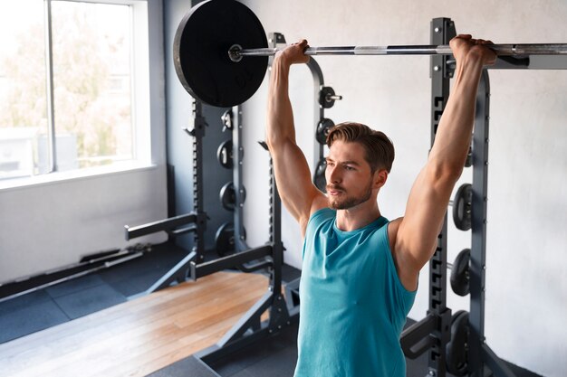 Jovem bonito treinando na academia para musculação