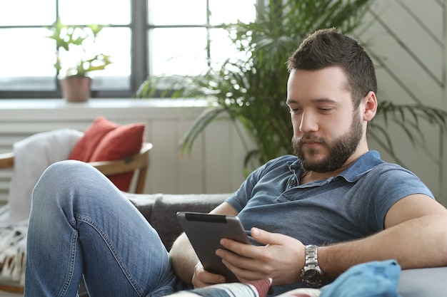 Jovem bonito usando tablet digital ou e-book