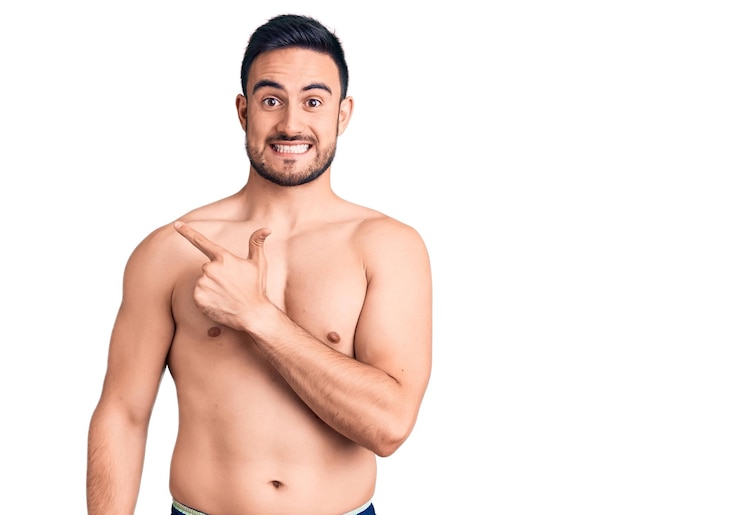 Foto grátis jovem bonito vestindo trajes de banho alegre com um sorriso no rosto apontando com a mão e o dedo para o lado com expressão feliz e natural