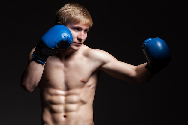 Jovem boxeador bonito em luvas azuis