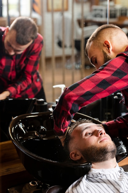 Jovem cabeleireiro lavando o cabelo do homem