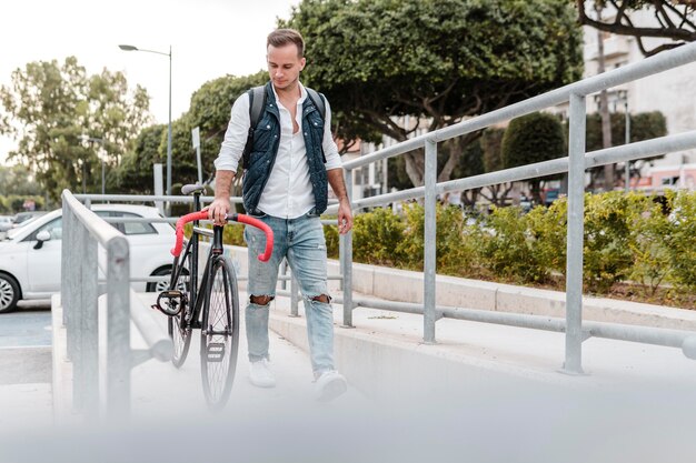 Jovem caminhando ao lado de sua bicicleta