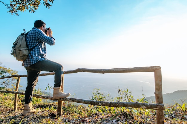 Jovem caminhante asiático e mochila usam câmera para tirar fotos no ponto de vista no espaço de cópia da floresta