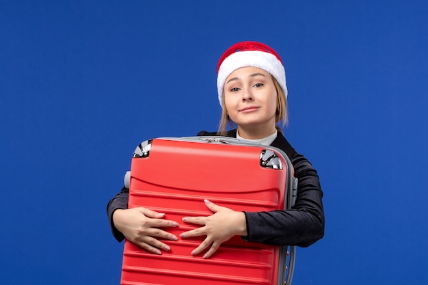 Jovem carregando uma grande sacola vermelha em uma viagem de férias de ano novo com parede azul