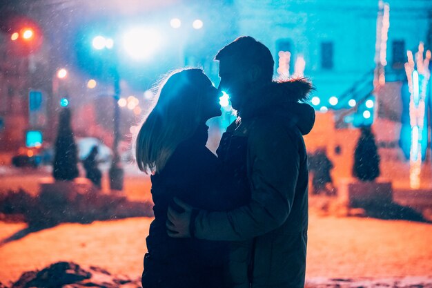 Jovem casal adulto nos braços um do outro na rua coberta de neve