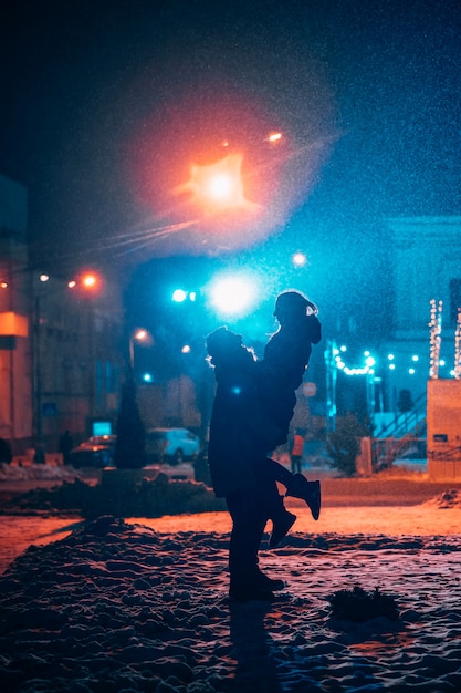 Jovem casal adulto nos braços um do outro na rua coberta de neve