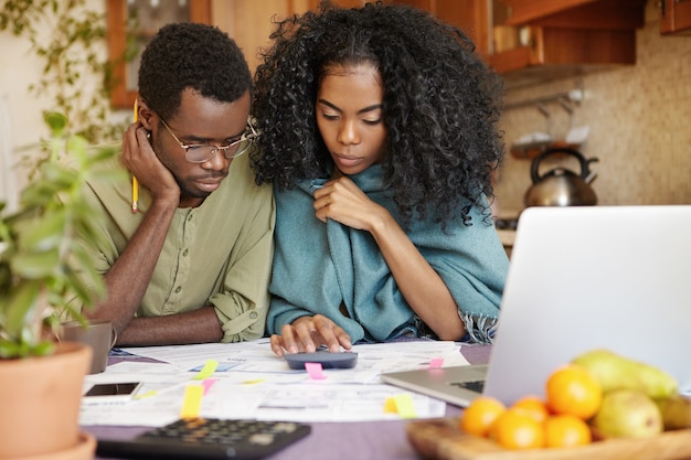 Foto grátis jovem casal afro-americano infeliz e deprimido calculando o orçamento familiar