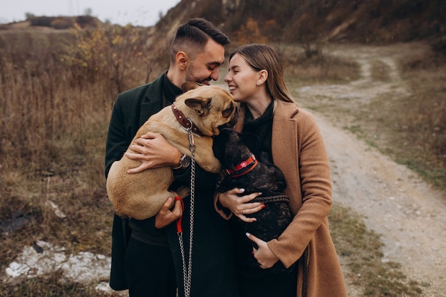 Foto grátis jovem casal andando seus bulldogs franceses no parque