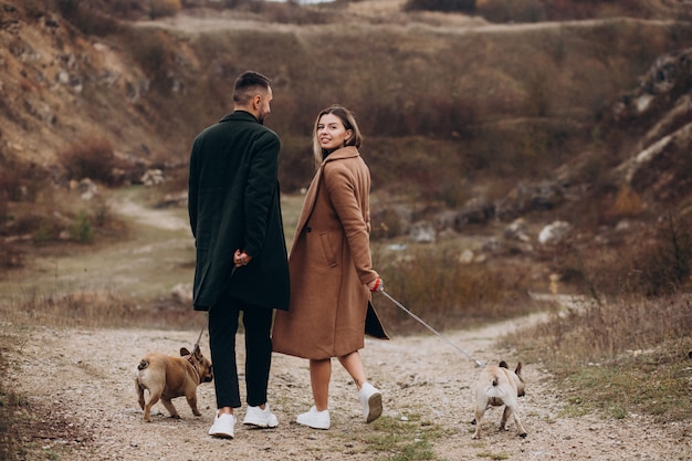 Jovem casal andando seus bulldogs franceses no parque