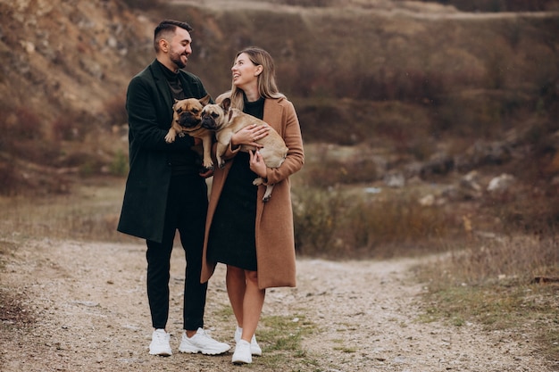 Jovem casal andando seus bulldogs franceses no parque