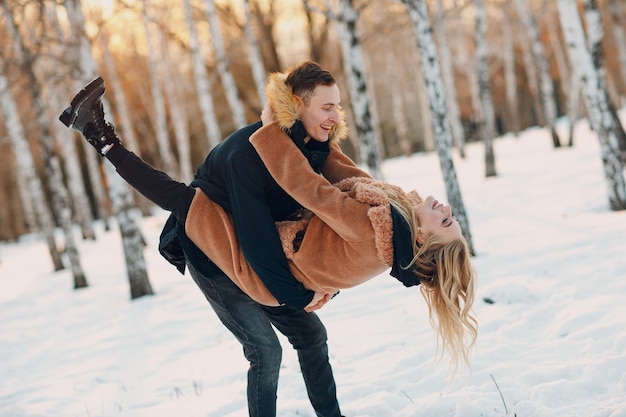 Jovem casal apaixonado andando, brincando e se divertindo no parque florestal de inverno