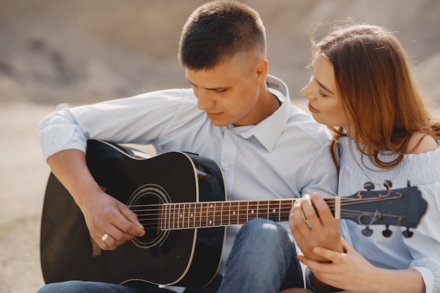 Jovem casal apaixonado, namorado tocando violão