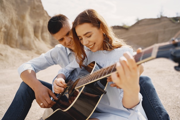 Jovem casal apaixonado, namorado tocando violão