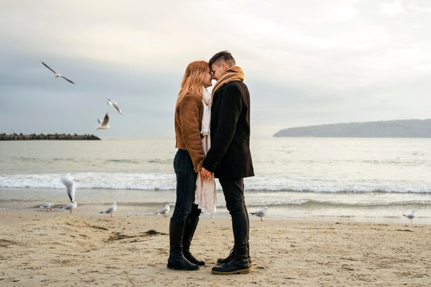 Jovem casal apaixonado no inverno na praia de mãos dadas