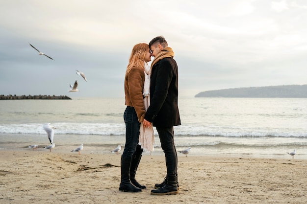 Jovem casal apaixonado no inverno na praia de mãos dadas