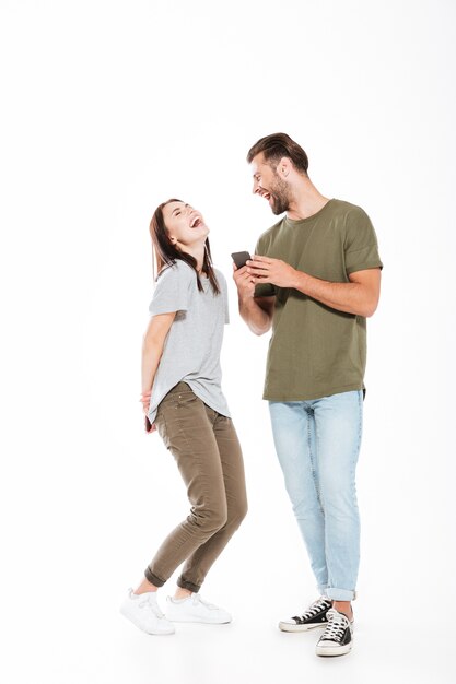Jovem casal apaixonado segurando os telefones a rir.