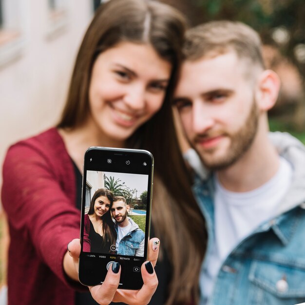 Jovem casal apaixonado tomando selfie no jardim