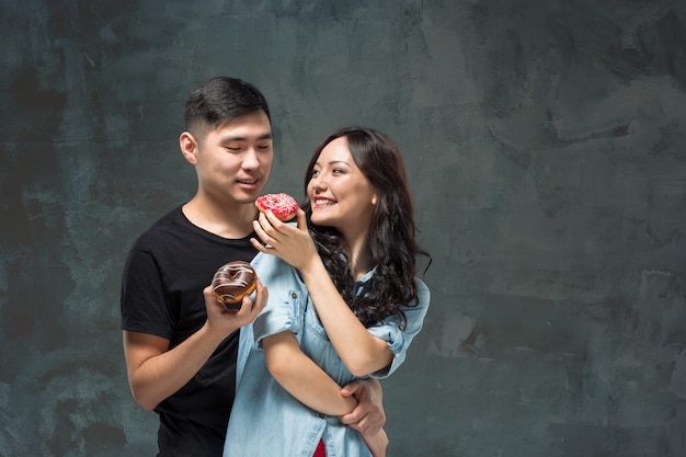 Jovem casal asiático gosta de comer doce rosquinha colorida