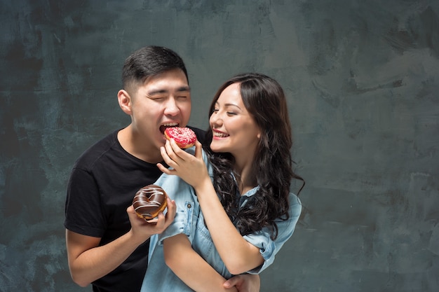 Jovem casal asiático gosta de comer doce rosquinha colorida