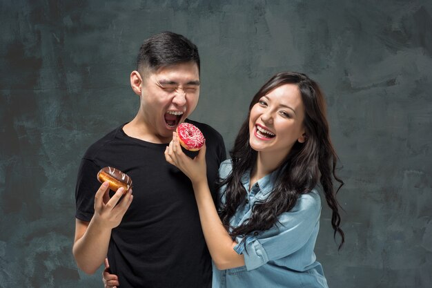 Jovem casal asiático gosta de comer rosquinha doce e colorida